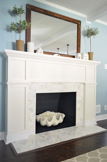 Refaced Brick Fireplace with White Marble Tile and Wood Trim Molding Mantel