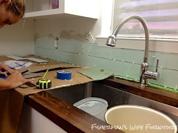 installing glass subway tile backsplash in small kitchen remodel, Fisherman's Wife Furniture featured on Remodelaholic.com
