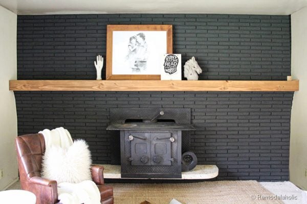 brick fireplace wall makeover painted black with an easy DIY wood mantel